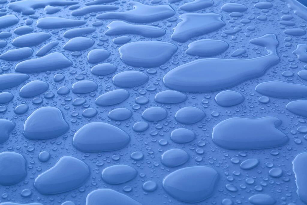 The Icy Scandi Living Room: How to Master the 2026 "Subzero" Look Closeup background of shiny blue surface with transparent liquid drops of different shapes