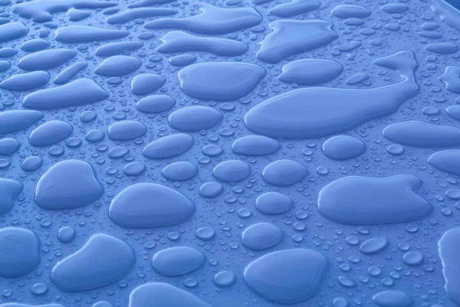 The Icy Scandi Living Room: How to Master the 2026 "Subzero" Look Closeup background of shiny blue surface with transparent liquid drops of different shapes